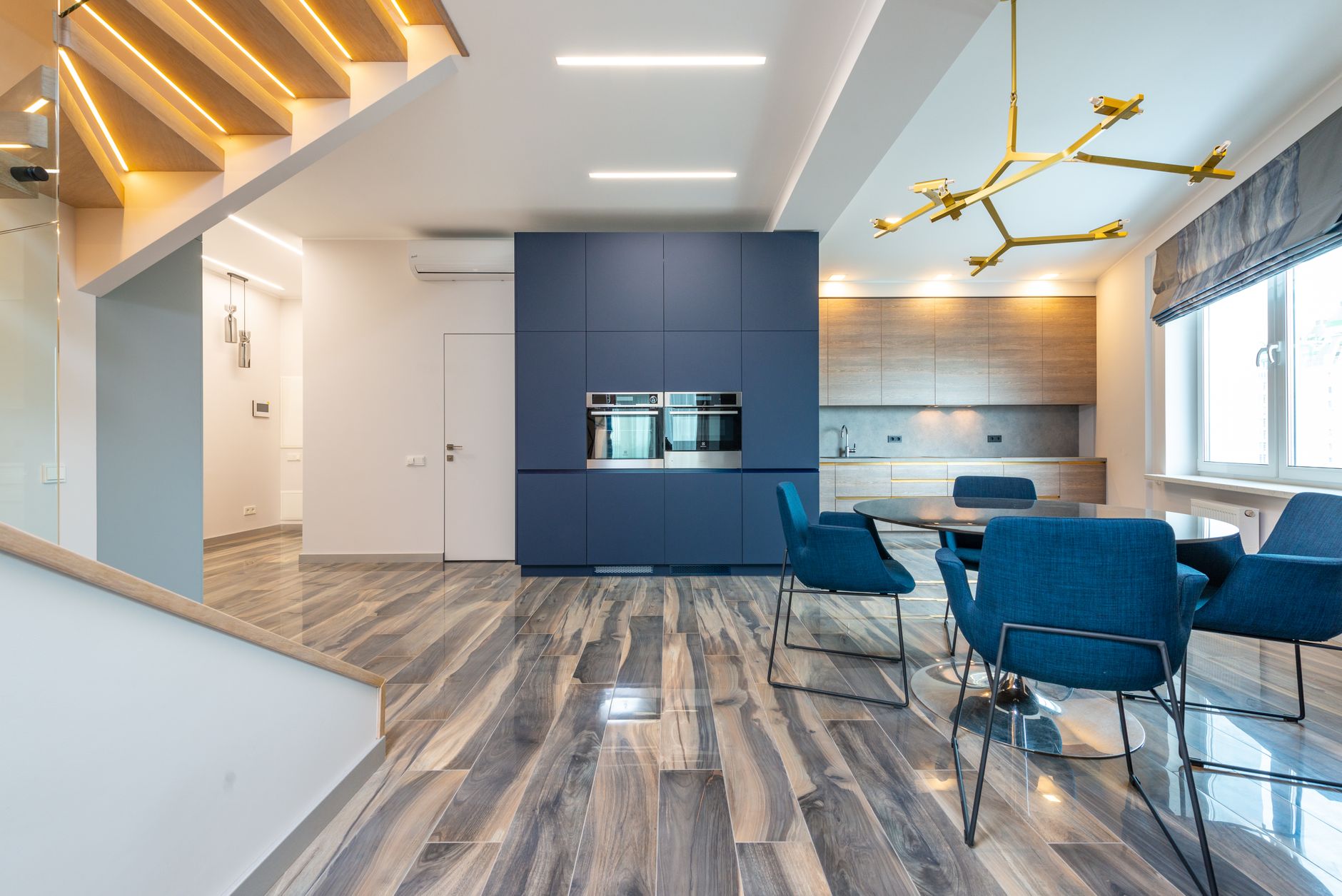 Table with armchairs on floor against cabinets and built in electric appliances in modern kitchen at home in Allen, TX