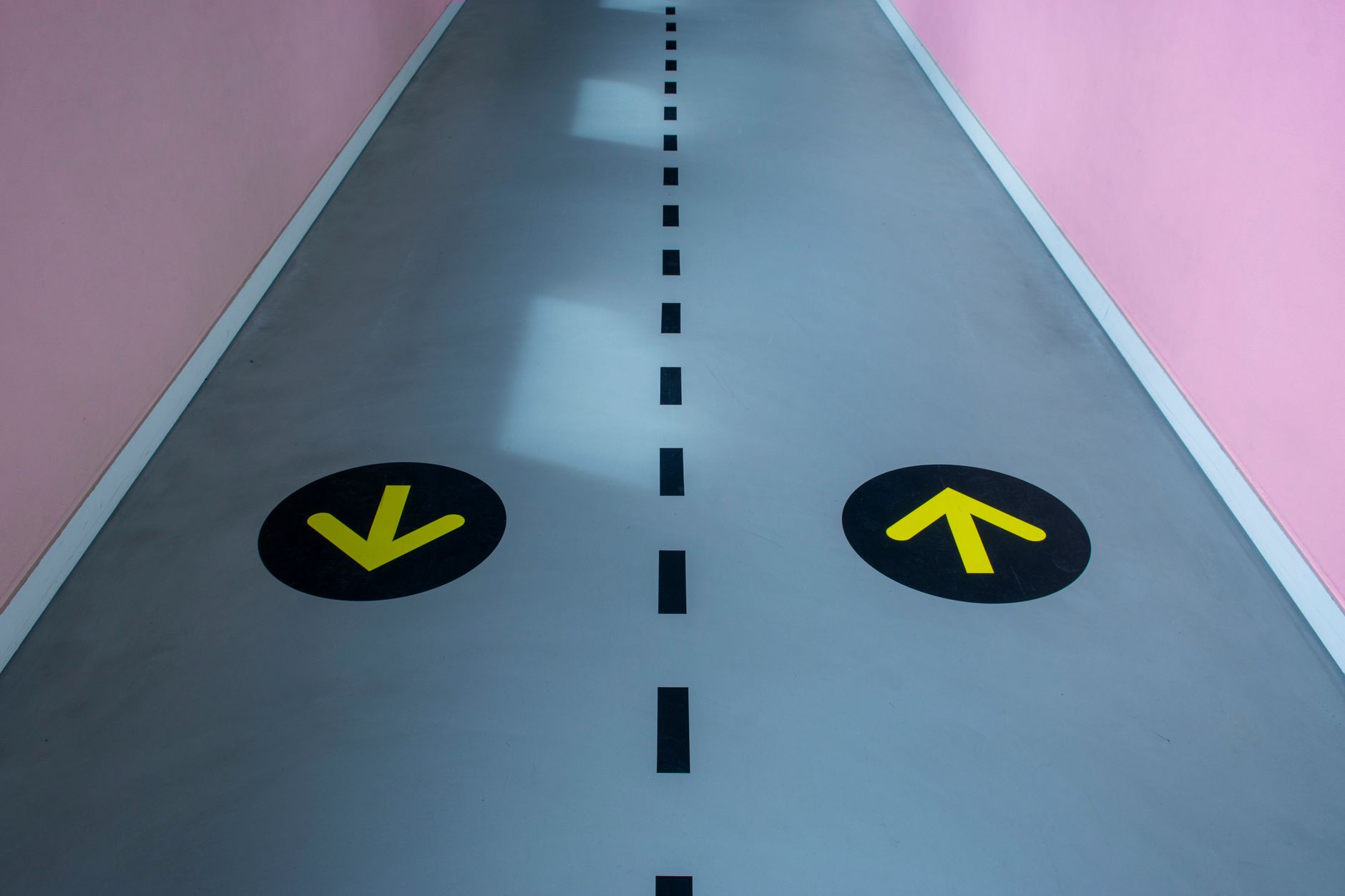 A vibrant corridor featuring contrasting pink walls and directional arrows on the floor for visual guidance in Allen, TX
